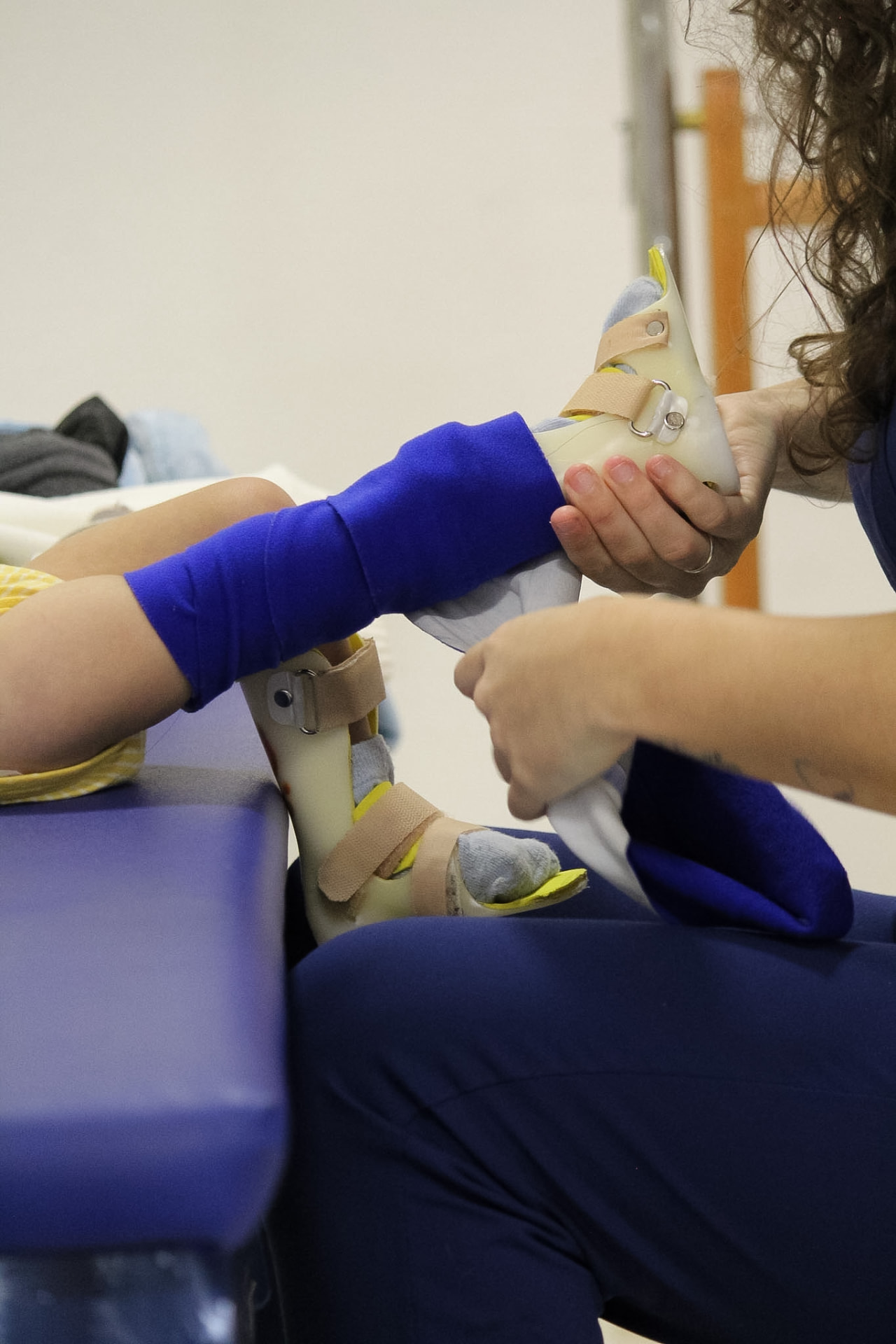 Fisioterapeuta colocando órtese personalizada na perna de uma criança
